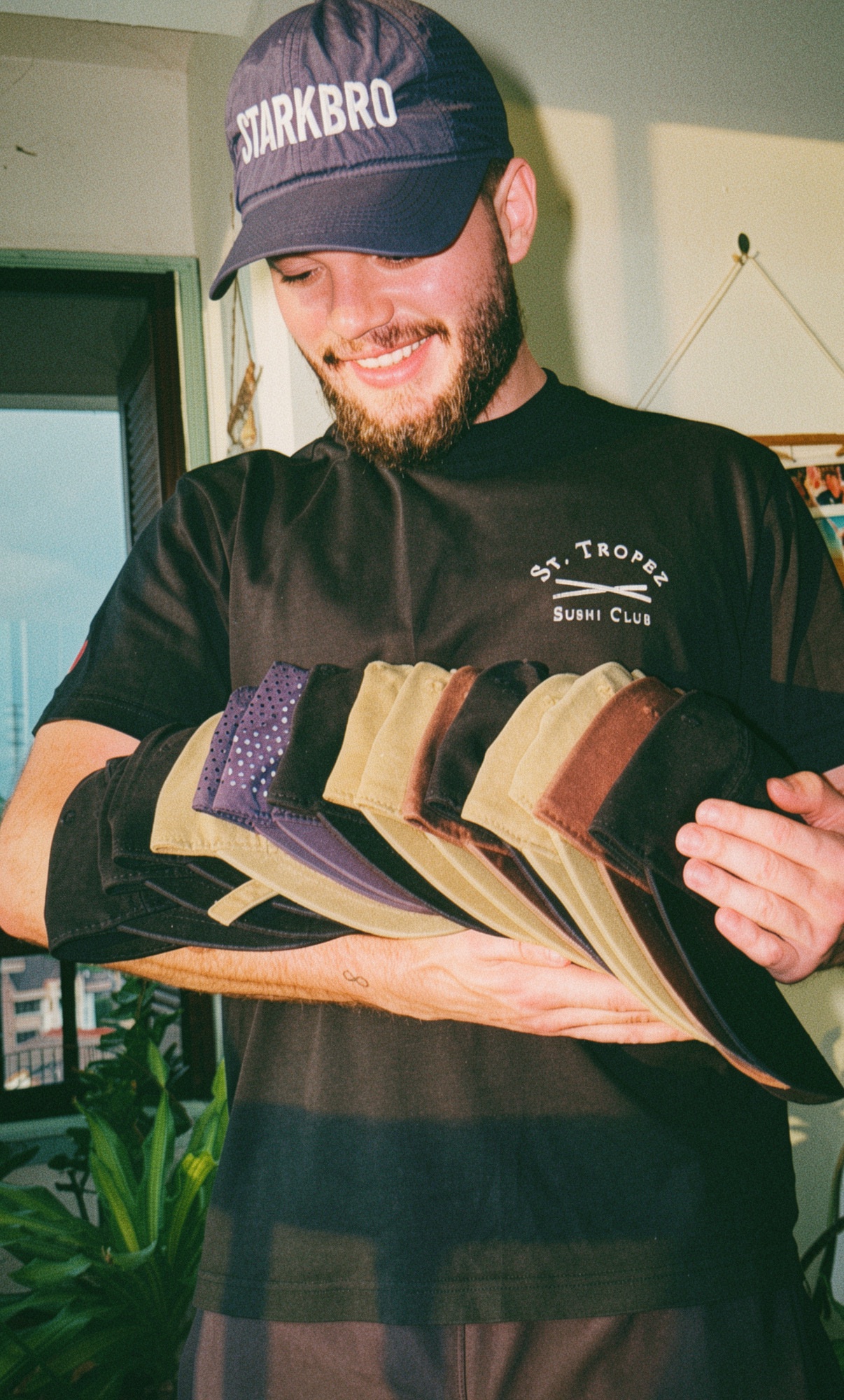 The founder carrying an armful of caps from his collection in warm evening light